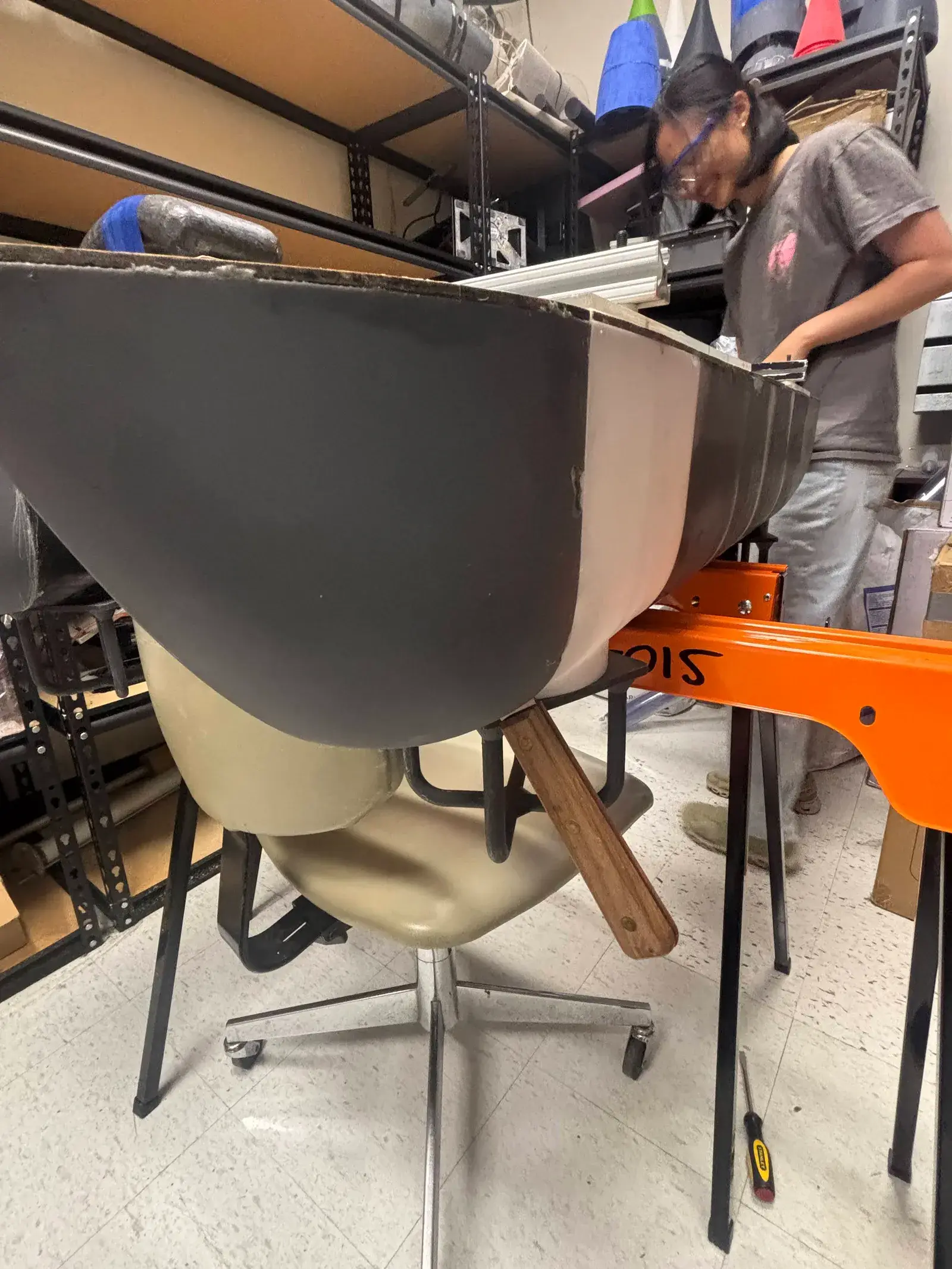 A printed hull section with its white bow module, held on an orange stand