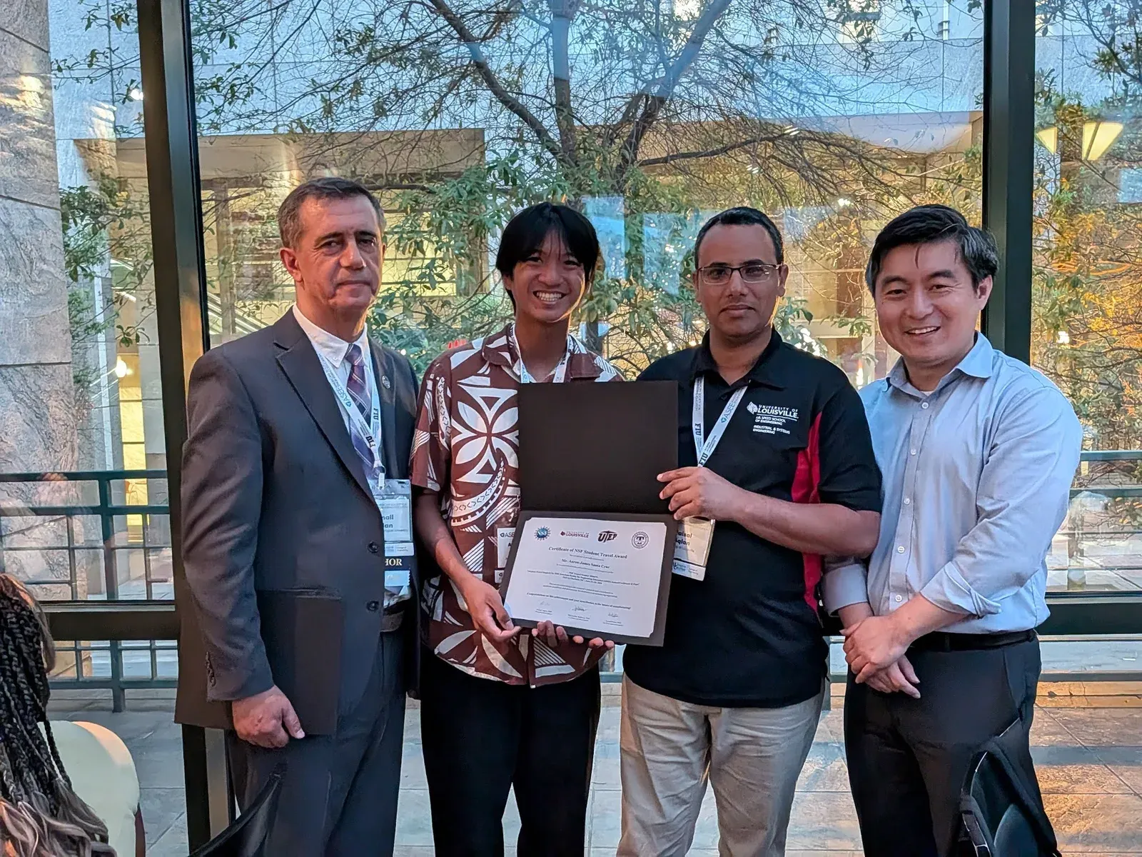 AJ receiving the NSF travel grant certificate with three presenters