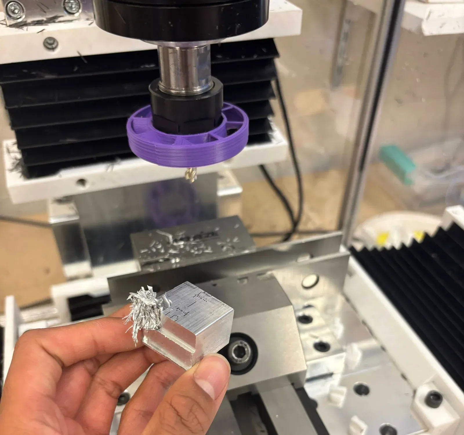 An aluminum test block held beside a benchtop mill after a cut