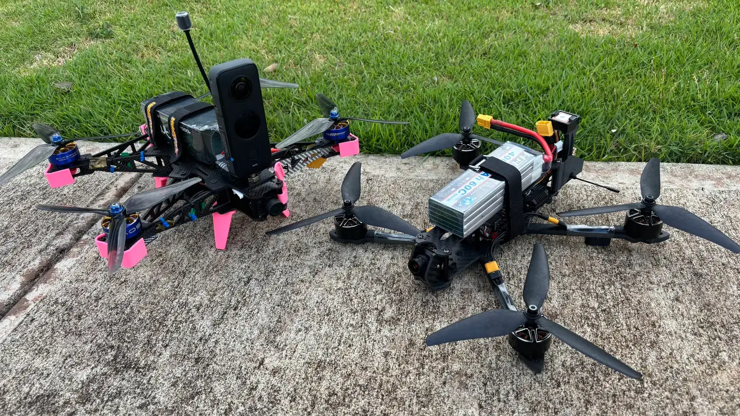 Two carbon-fiber drones on a curb: the 360° capture build carrying an Insta360 camera, and a second quad