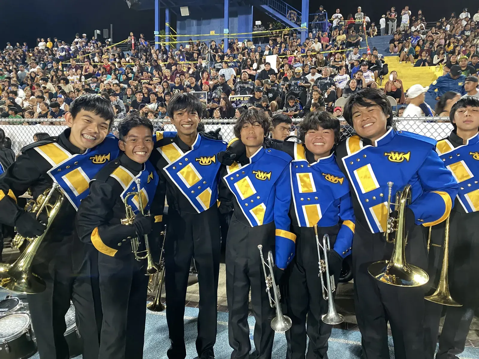 Marching band in blue and gold uniforms in a stadium