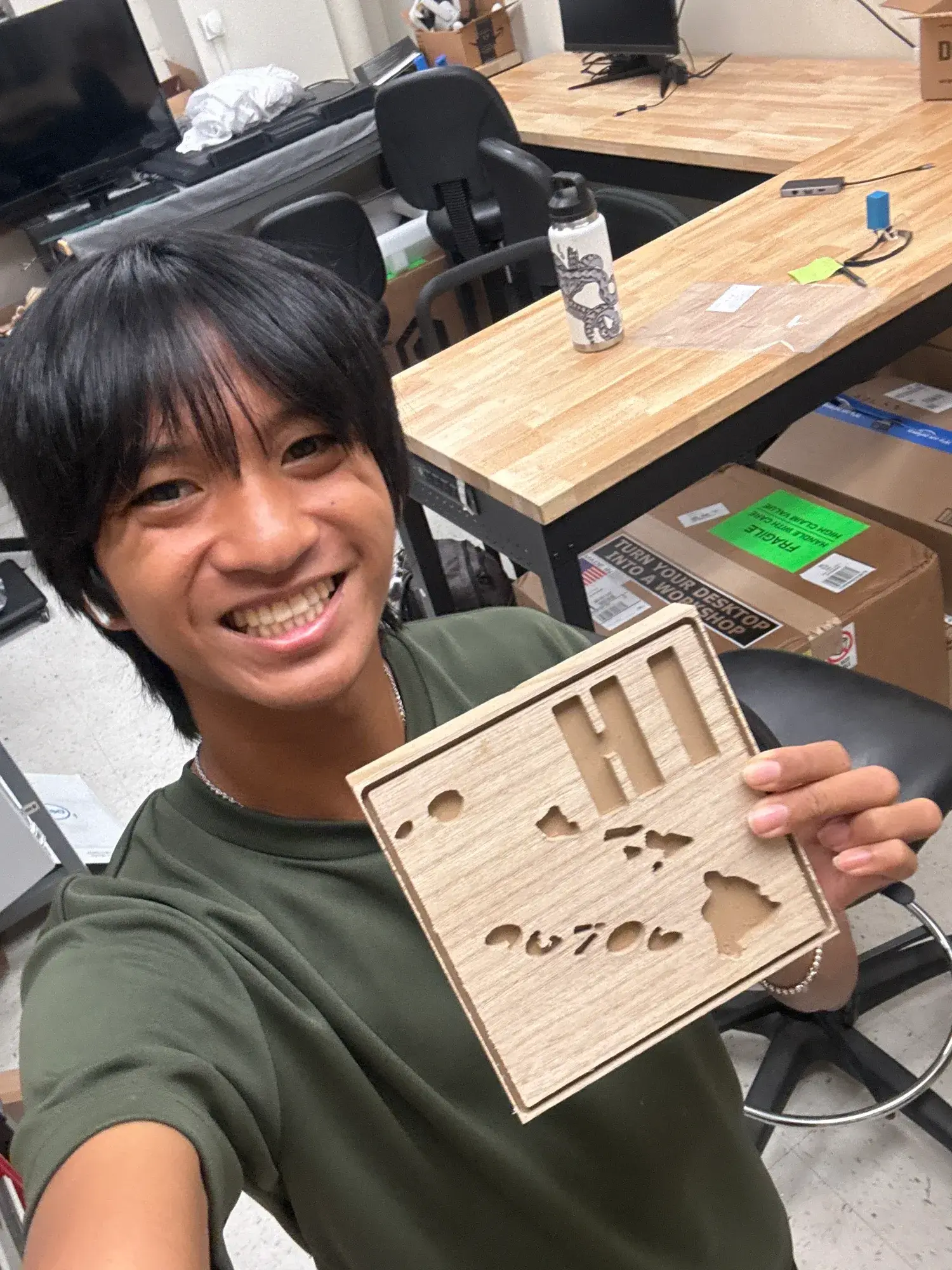 AJ holding a wooden Hawaii plate cut on the desktop CNC