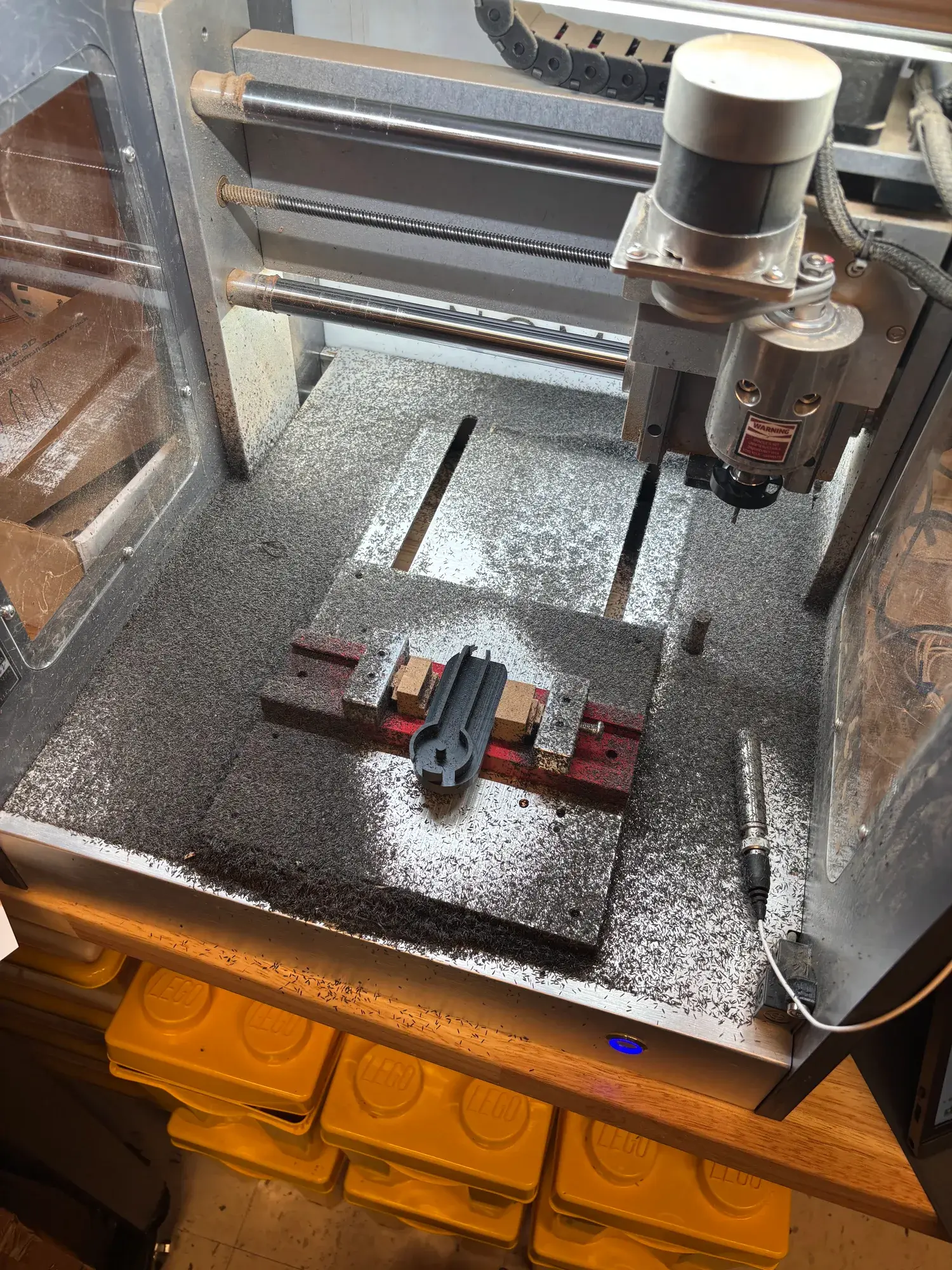 An aluminum part held in a vise inside the machine, surrounded by chips