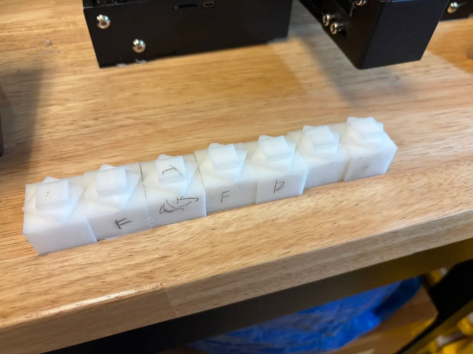A row of machined white plastic parts on the bench
